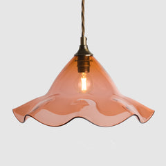 Pendant light with wavy peach glass shade on a white background
