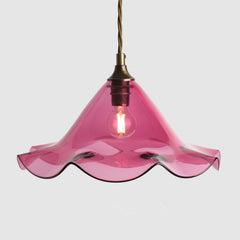 Pink glass pendant light with a wavy design on a white background