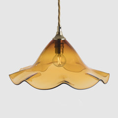 Amber glass pendant light with gold fixture on a white background