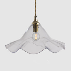 Clear glass pendant light with brass fixture on a white background