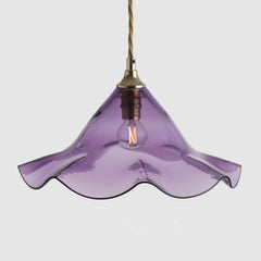 Purple pendant light with a gold fixture on a light gray background