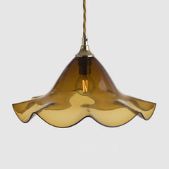 Amber glass pendant light with a gold fixture on a white background