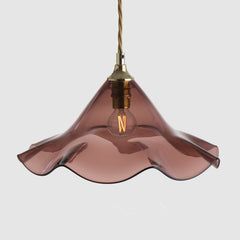 Pink glass pendant light with a gold fixture on a white background