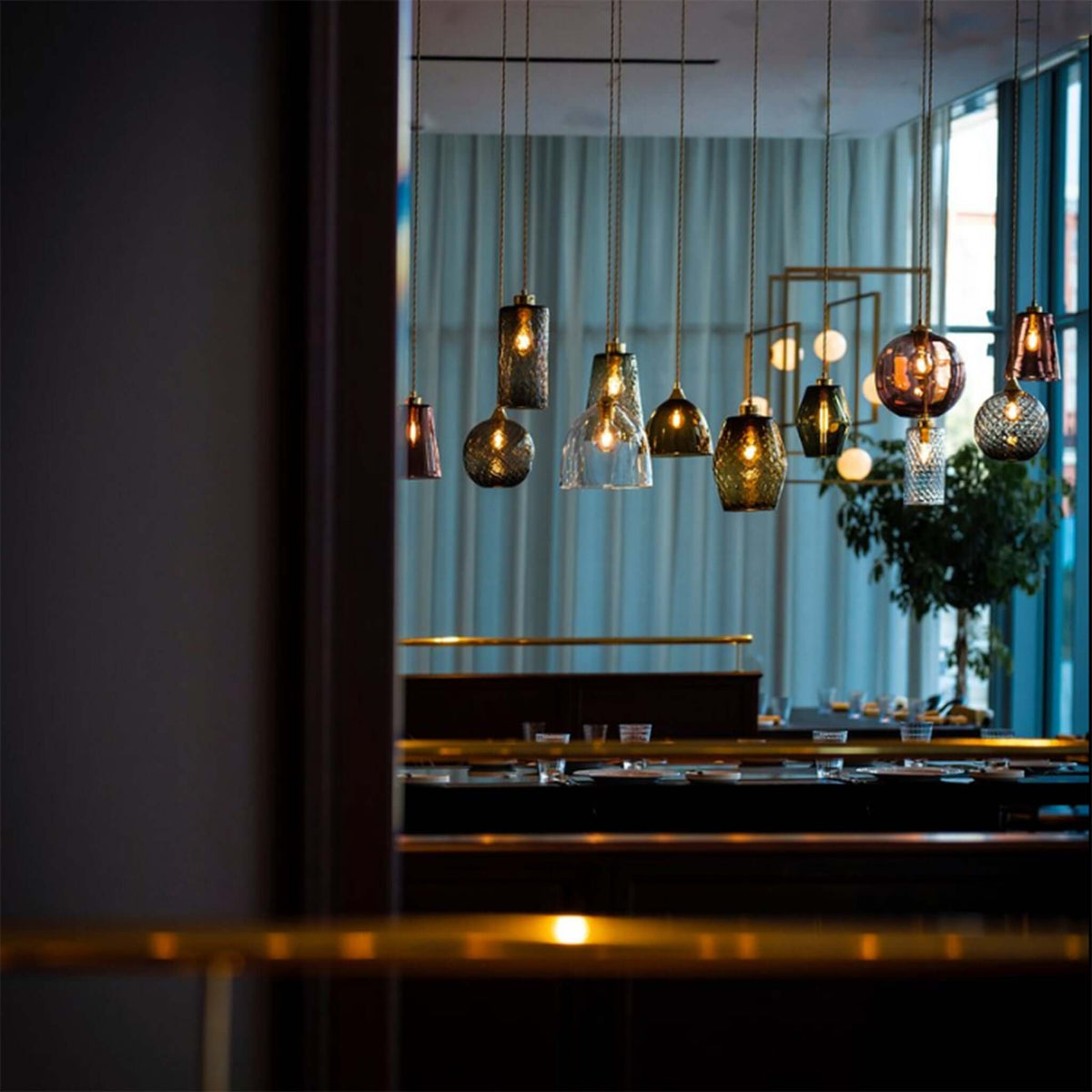Multiple coloured glass lights hanging over a table