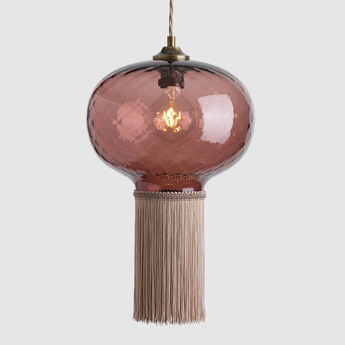 Pink glass hand blown glass pendant light with fabric fringe and antique brass