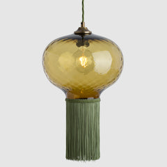 Pendant light with amber glass shade and green tassel on a white background