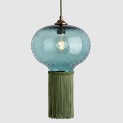 Blue glass pendant light with green tassel on a white background
