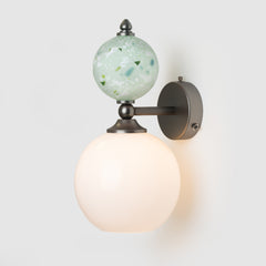 Wall-mounted light fixture with glass globe on a white background