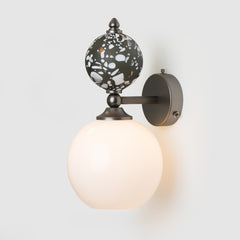Wall-mounted light fixture with decorative shade on a white background