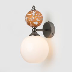 Wall-mounted light fixture with terracotta-colored glass shade on a white background