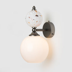 Wall-mounted light fixture with glass globe on a white background