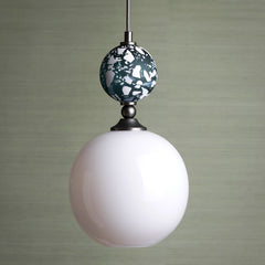 Pendant light with a white glass globe and decorative Terrazzo top on a neutral background