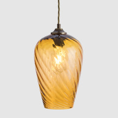 Twisted optic amber glass pendant light on a white background