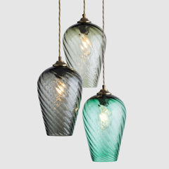 Three green glass pendant lights with gold fixtures on a light grey background