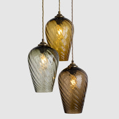Three hanging glass lights with a textured design on a light gray background