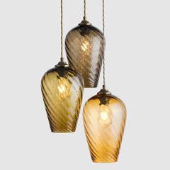 Three hanging glass lamps with a warm glow on a light gray background