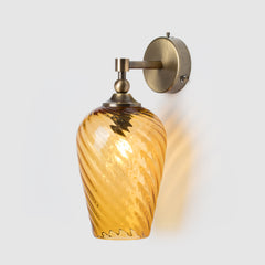 Wall-mounted light fixture with amber glass shade on a white background