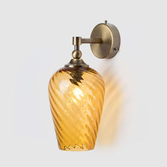 Wall-mounted light fixture with amber glass shade on a white background