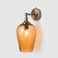Decorative wall sconce with hand-blown twisted glass shade and antique brass fixture