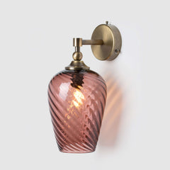 Decorative wall sconce with hand-blown pink twisted glass shade and antique brass fixture