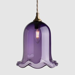 Bell shaped coloured glass light shade with frilled bottom on twisted fabric covered flex