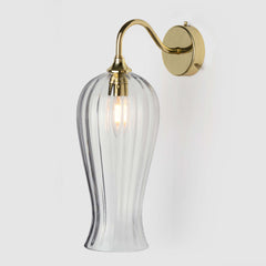 Long coloured optic glass light shade on a wall arm in polished brass