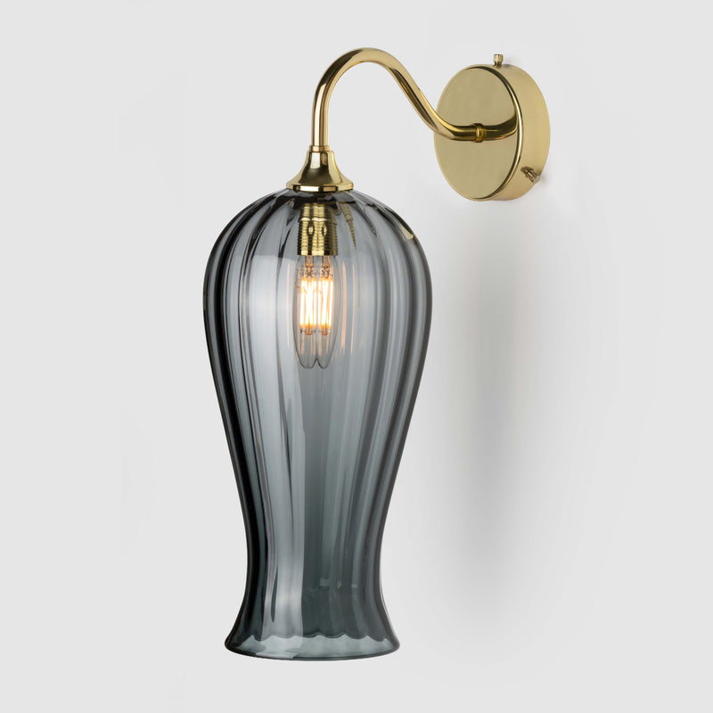 Long coloured optic glass light shade on a wall arm in polished brass