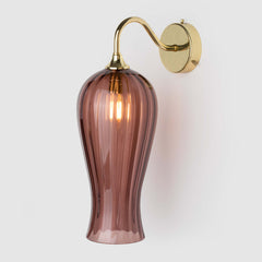 Long coloured optic glass light shade on a wall arm in polished brass