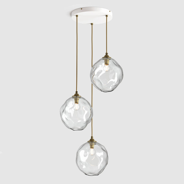 Clear organic shaped glass pendant lights hanging on ceiling plate with fabric covered flex