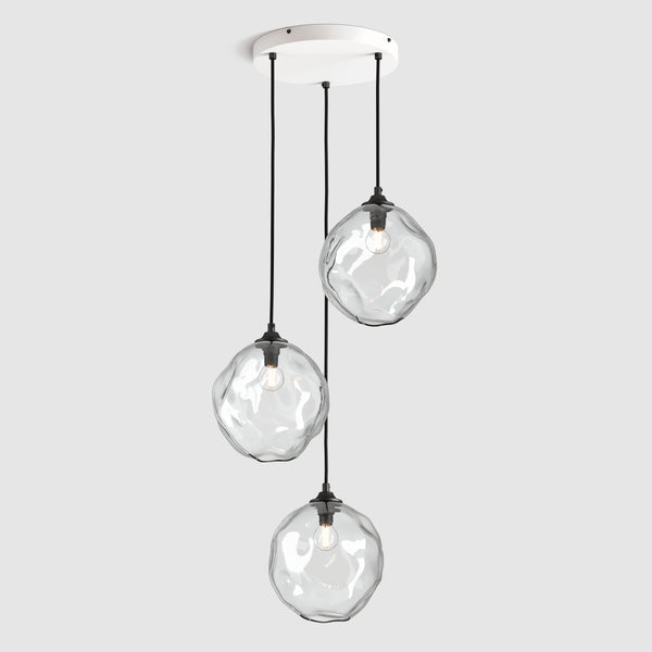 Clear organic shaped glass pendant lights hanging on ceiling plate with fabric covered flex
