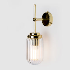 Clear ribbed glass light shade on a polished brass wall lamp