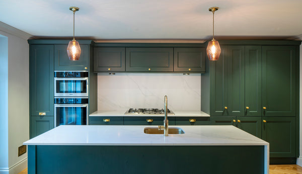 Green kitchen with feature glass pendant lighting and brass hardware