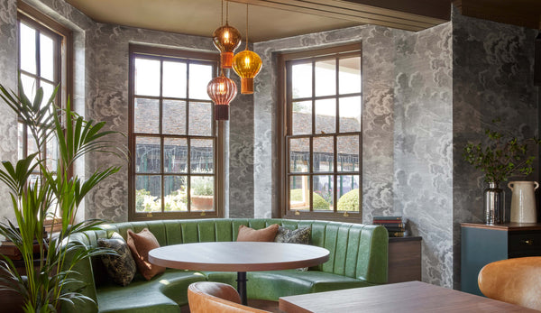 Coloured glass pendant lighting by Rothschild & Bickers hanging over a table in window seating area by Faber for the George Hotel, Cambridgeshire