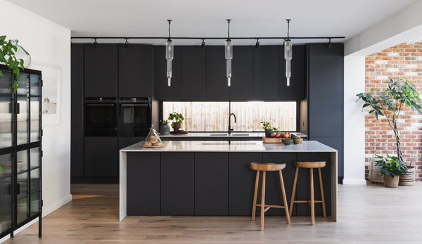 Matte black kitchen with reeded clear glass pendants by Rothschild & Bickers over island
