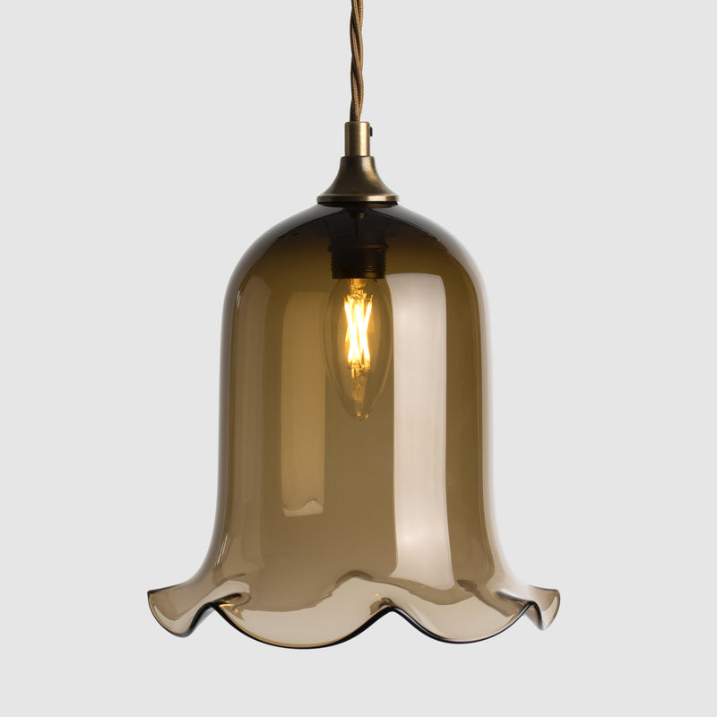 Bell shaped coloured glass light shade with frilled bottom on twisted fabric covered flex