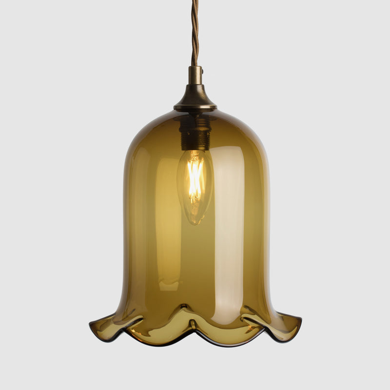 Bell shaped coloured glass light shade with frilled bottom on twisted fabric covered flex