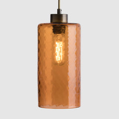 Cylinder pendant light with a peach textured glass shade on a grey background