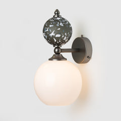 Wall-mounted light fixture with decorative glass shade on a white background