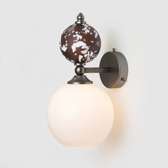 Wall-mounted light fixture with decorative glass shade on a white background