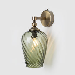 Wall-mounted light fixture with green glass shade and brass finish on a white background