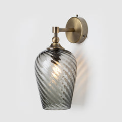 Decorative wall light with hand-blown twisted glass shade and antique brass fixture