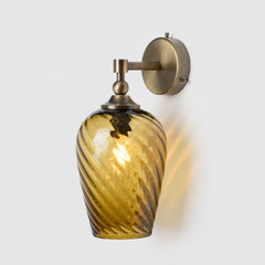 Decorative wall sconce with hand-blown twisted glass shade and antique brass fixture