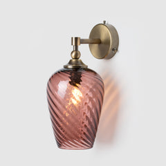Decorative wall sconce with hand-blown pink twisted glass shade and antique brass fixture