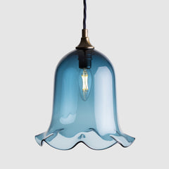Ball shaped coloured glass light shade with frilled bottom on twisted fabric covered flex