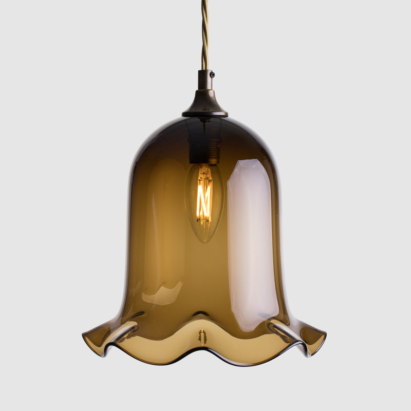 Ball shaped coloured glass light shade with frilled bottom on twisted fabric covered flex