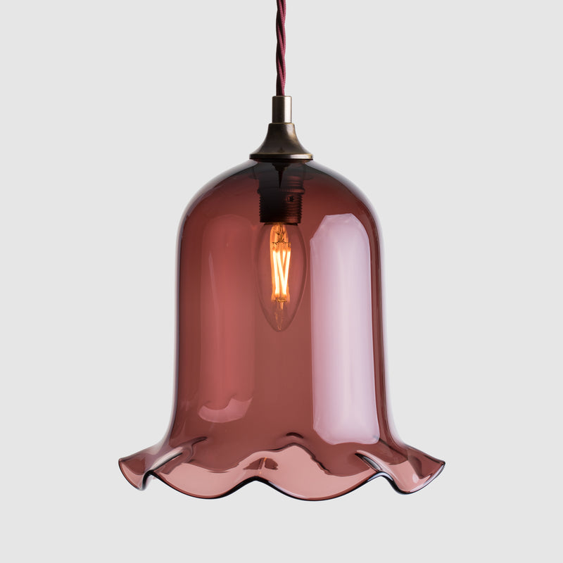 Bell shaped coloured glass light shade with frilled bottom on twisted fabric covered flex