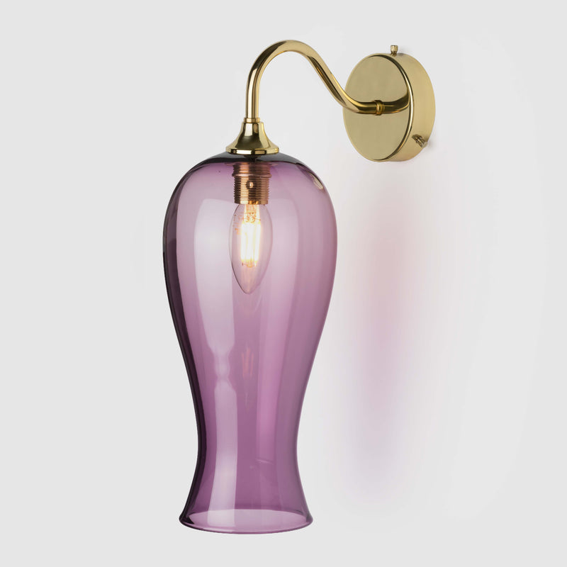 Long coloured glass light shade on a wall arm in polished brass