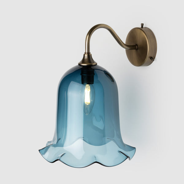 Denim blue blown glass light shade with frilled bottom on an antique brass wall arm