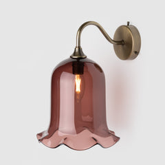 Tea coloured blown glass light shade with frilled bottom on an antique brass wall arm