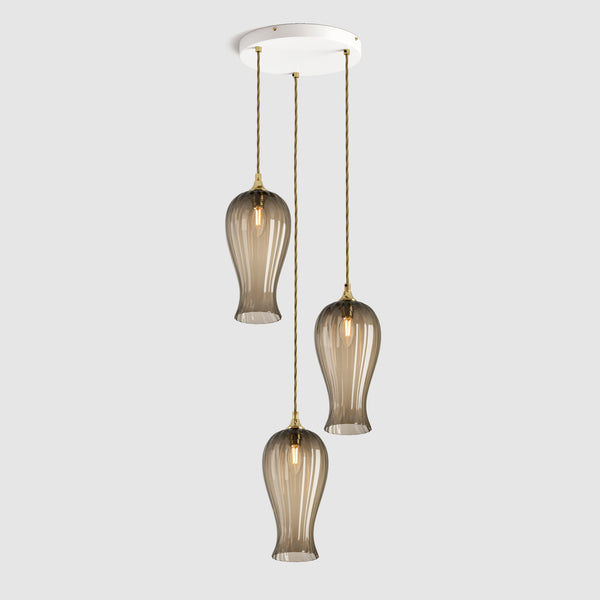 Group of Long ribbed bronze coloured glass decorative pendant lights with brass fitting and fabric covered flex, hanging on a ceiling plate
